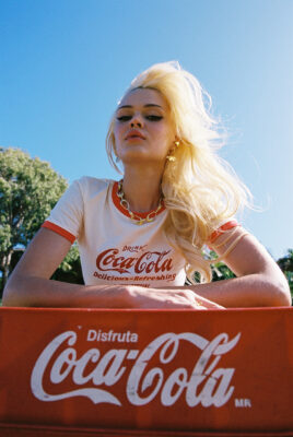 model ayla leaning on coke crates posing with sun in hair